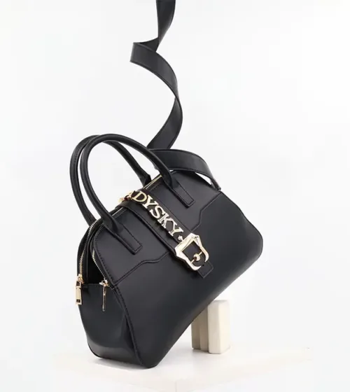 Elegantna crna torba Noire D’Opéra sa zlatnim metalnim detaljima i širokim kaišem, postavljena na beloj pozadini