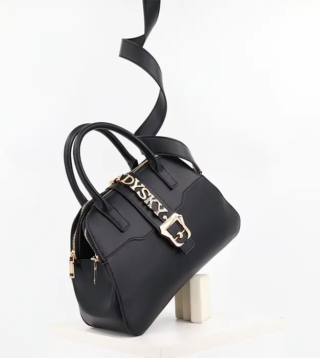 Elegantna crna torba Noire D’Opéra sa zlatnim metalnim detaljima i širokim kaišem, postavljena na beloj pozadini