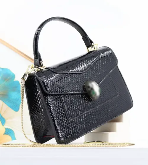 Ženska crna crossbody torba Serpentina Noir sa sjajnom teksturom i dekorativnim kopčanjem